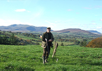 man standing in a field with mountains in the background